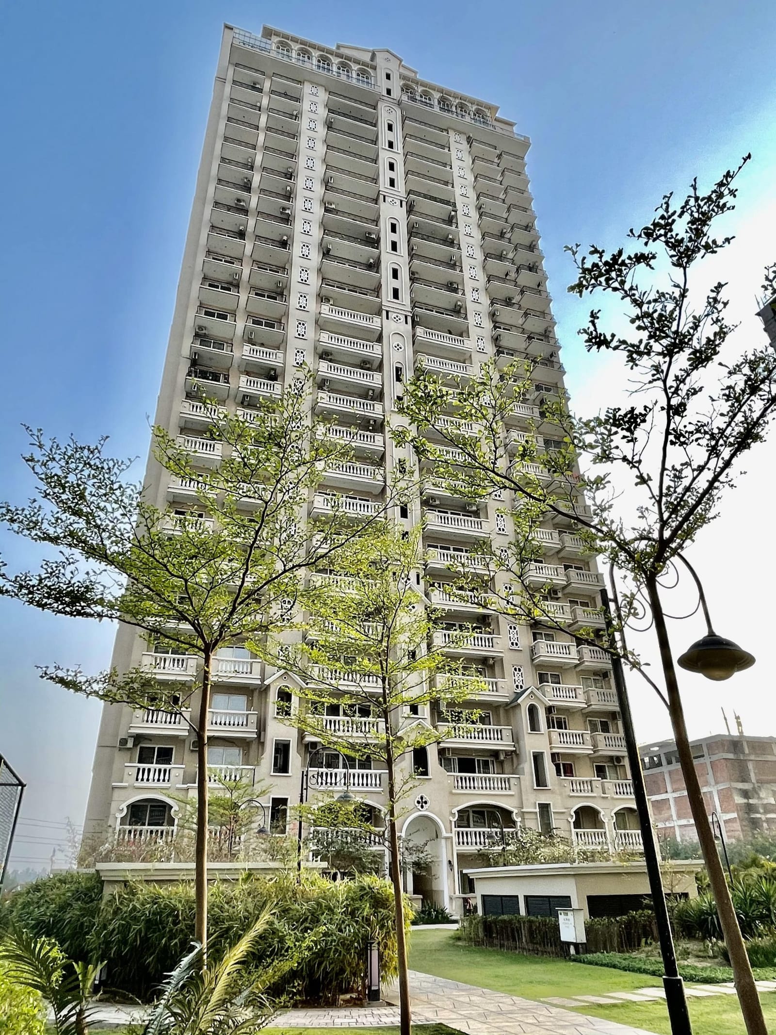 Photograph looking up at an ATS Casa Espana tower framed by trees and a lamp post
