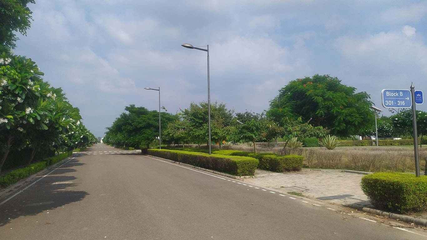 Photograph of an internal road with street lights, hedges and a Block B signboard in DLF Hyde Park Estate, New Chandigarh
