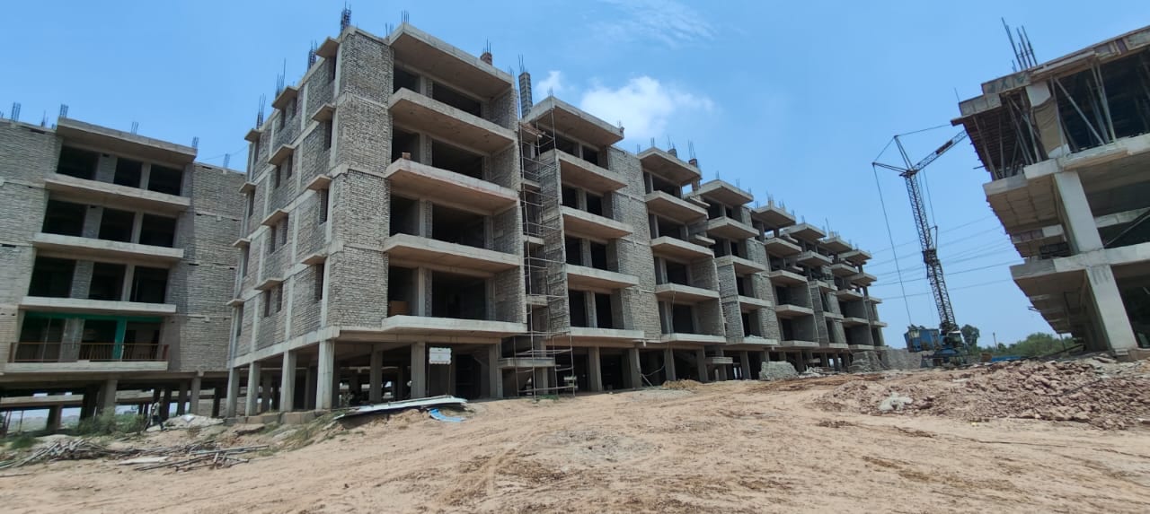 Construction photo of GMI Elite Homes, Banur, in June 2026 — brick-and-concrete stilt + 4 buildings under construction with a tower crane