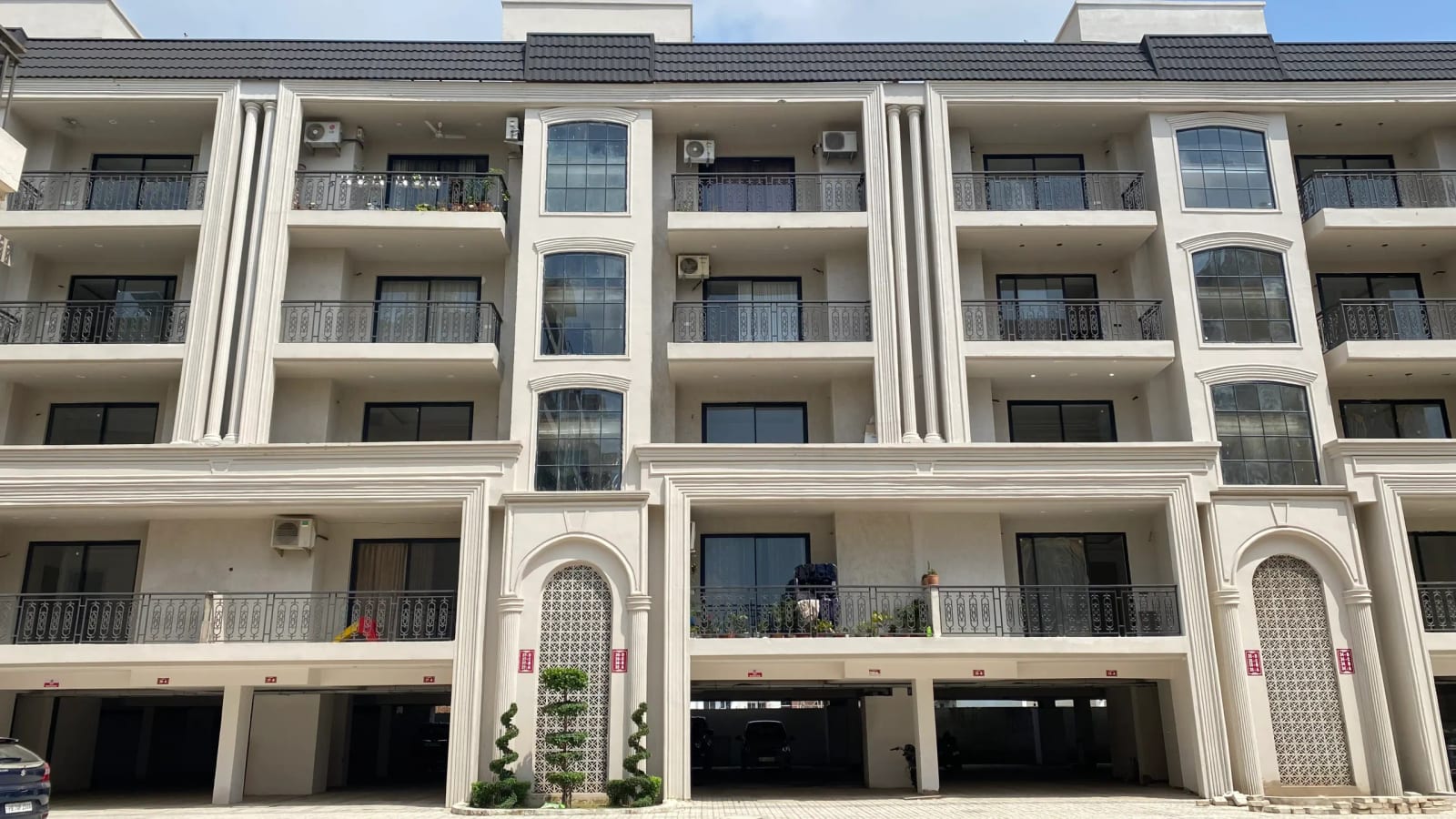 Daytime photograph of the completed Golden Castle building in Zirakpur showing balconies, arched jali panels and stilt parking.