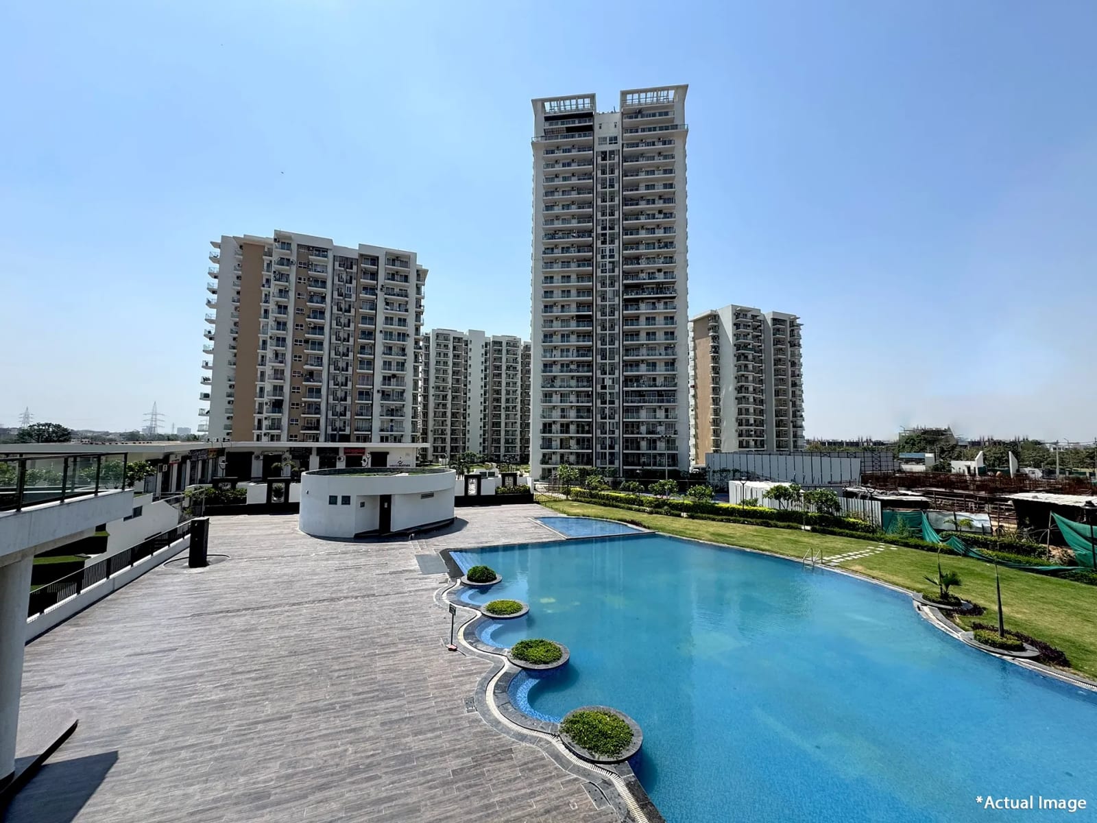 Actual photo of the swimming pool and deck at the Hero Homes clubhouse, Sector 88, Mohali, with Phase 1 towers behind