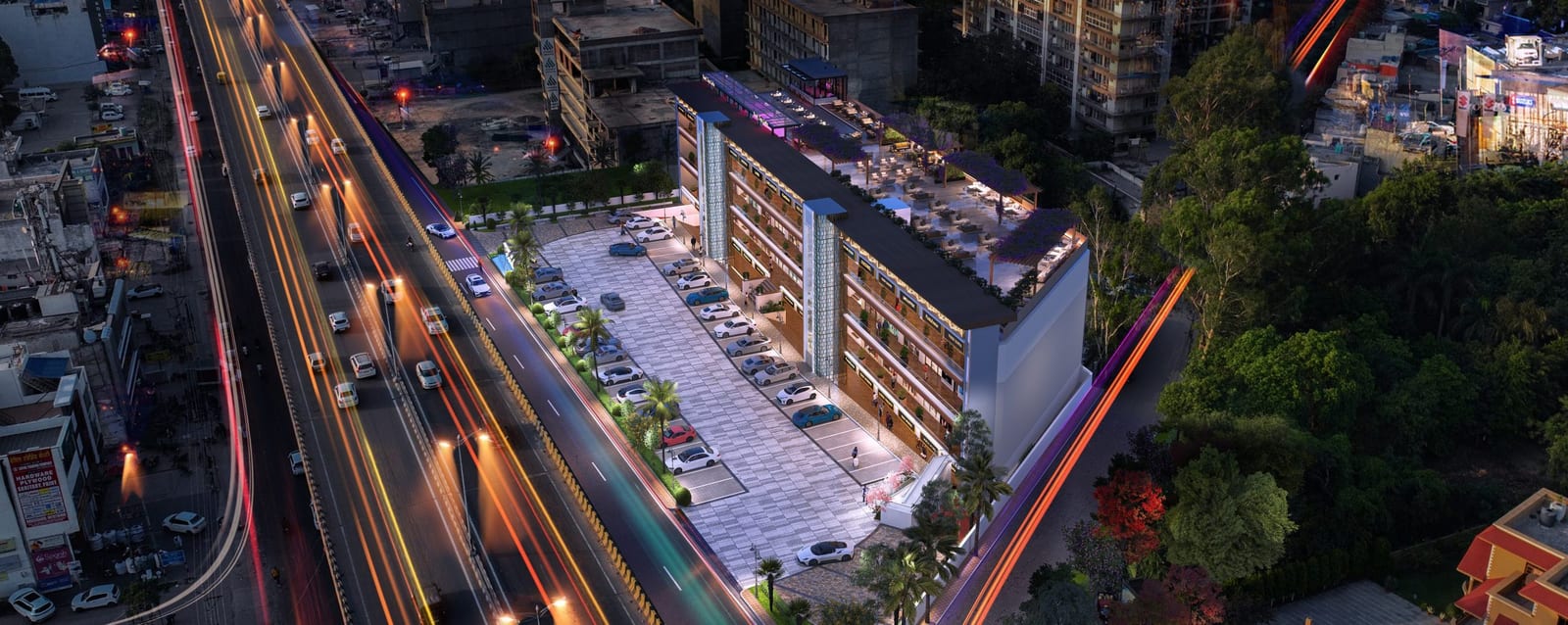 Night aerial view of JMR City Walk beside the Chandigarh-Ambala highway flyover, showing the forecourt car park and rooftop terrace