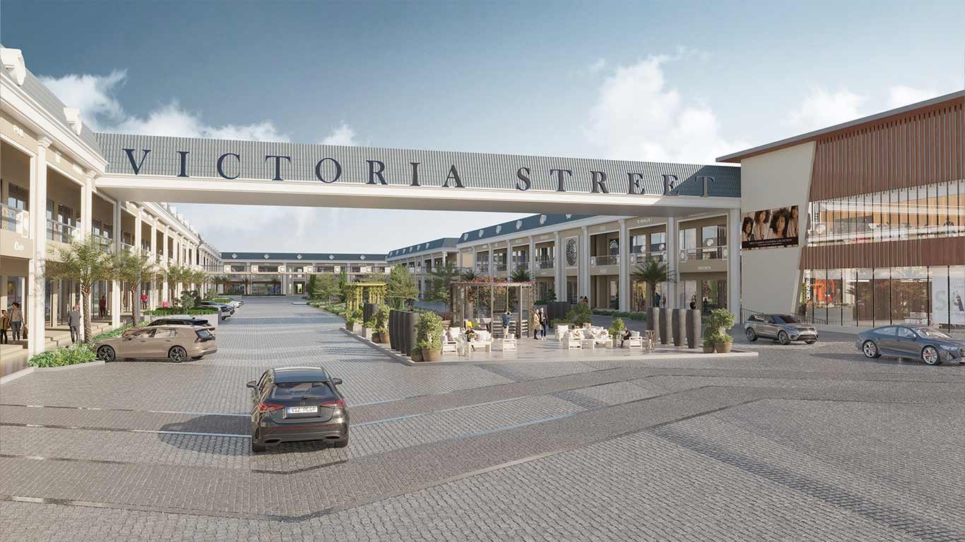 Entrance gateway bridge lettered Victoria Street spanning the paved high street, with showroom rows on both sides and a seating plaza, at Victoria Street, Sirhind.